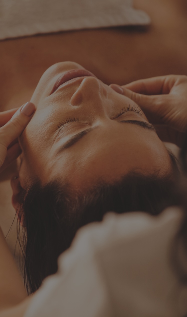A woman receives a facial massage at a spa within a treatment center.
